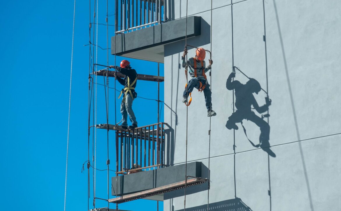 Couple of workers fixing and climbing a scaffolding while following all the safety measures